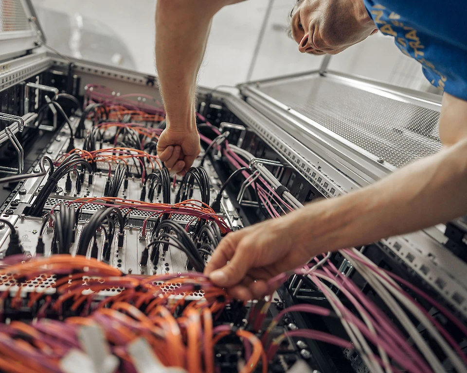 Hofmann-Techniker verkabelt Netzwerkkabel und überprüft Verbindungen in einer IT-Infrastruktur.