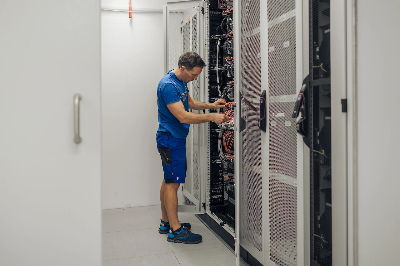 Techniker überprüft und organisiert Serverkabel in einem IT-Logistikzentrum.