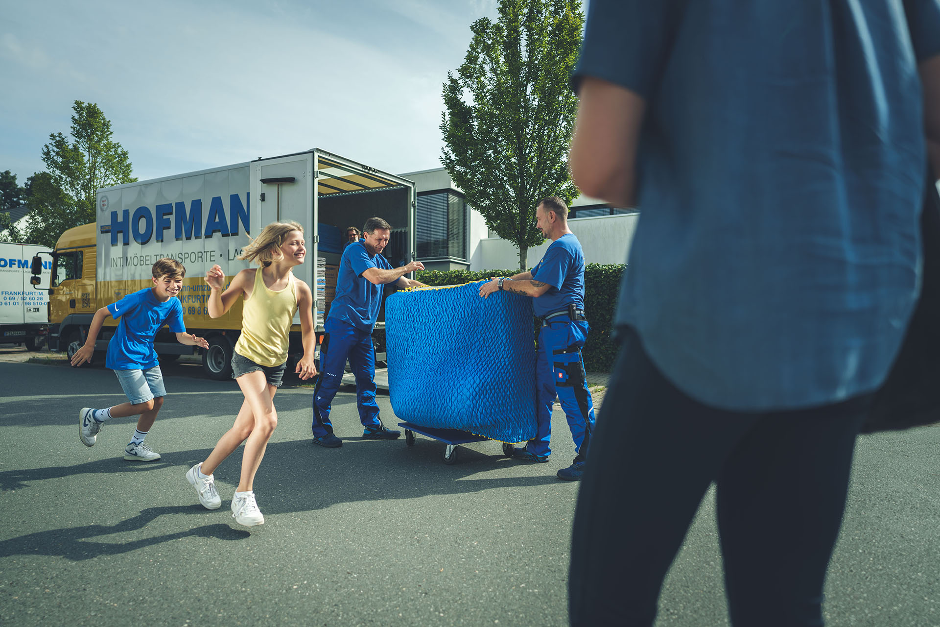 Hofmann-Team bei der Arbeit, Kinder spielen fröhlich daneben und Eltern schauen entspannt zu.