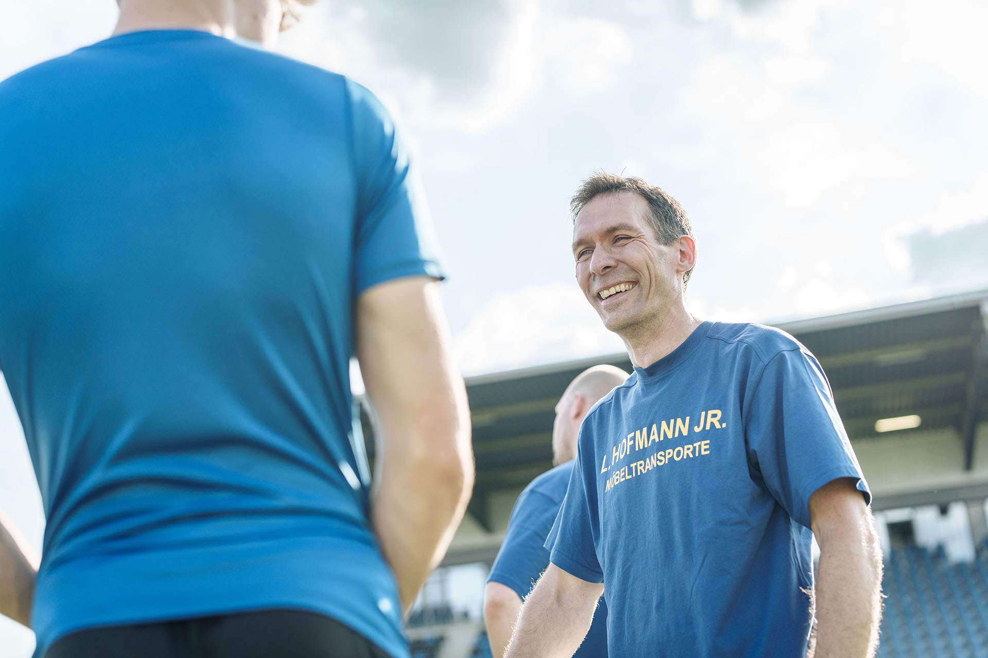 Hofmann-Mitarbeiter in lockerer Unterhaltung auf einem Spielfeld.